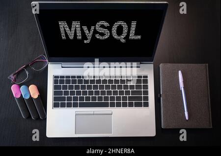 Vista dall'alto del laptop con testo MySQL. Iscrizione MySQL sullo schermo e sulla tastiera del laptop. Impara il linguaggio MySQL, i corsi per computer, la formazione. Foto Stock