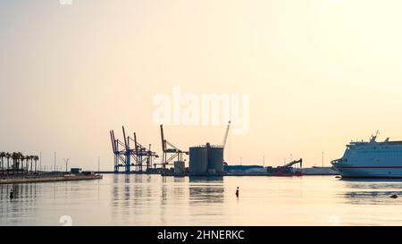 Sagome delle gru nel porto di Malaga al crepuscolo Foto Stock
