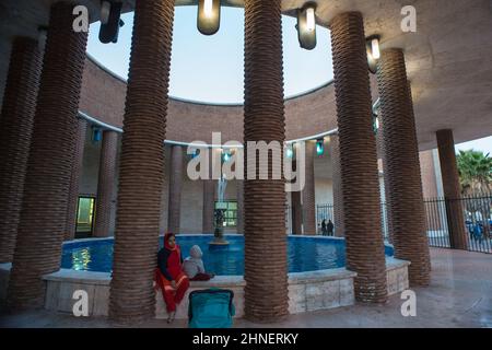 Lido di Ostia, Roma, Italia 18/10/2017: Madre asiatica con figlio seduta sul bordo della fontana, ufficio Poste Italiane. © Andrea Sabbadini Foto Stock