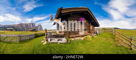 Vista panoramica della campagna agricola collinare con case in legno a Seiser Alm, il gruppo di Sciliar con Monte Petz (a sinistra) e Santnerspitze (a destra). Foto Stock