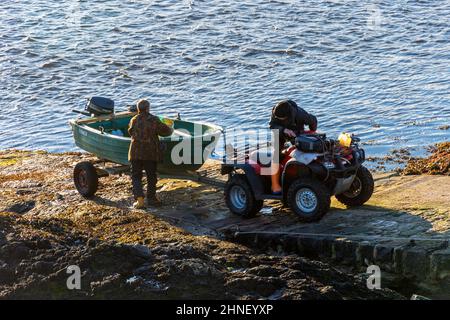 Due uomini lanciano una barca da un rimorchio sul molo di Keoldale, sulla Kyle of Durness, Sutherland, Scozia, Regno Unito. Foto Stock