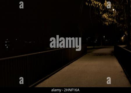 Passaggio su un ponte su un lago in un parco di notte Foto Stock