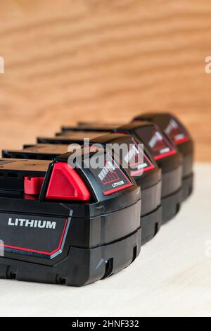 Batteria per trapano cordless. Batteria del cacciavite. Quattro batterie con indicatore di carica sono disposte su uno sfondo di legno Foto Stock