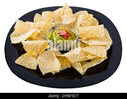 Mais patatine nachos con salsa guacamole fatta in casa su piatto nero Foto Stock