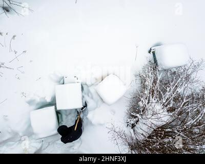 Un apicoltore che rimuove la neve intorno ai suoi alveari, vista aerea Foto Stock