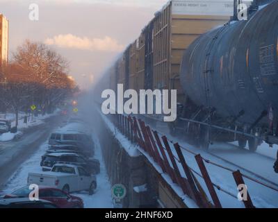 Un treno merci di passaggio sulla linea Union Pacific West a Oak Park, Illinois, spinge la neve appena caduta sulle auto sottostanti. Foto Stock