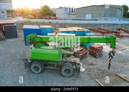 Sollevamento del trattore a gru in cantiere industriale. Macchinari per impieghi pesanti per l'edilizia. Foto Stock