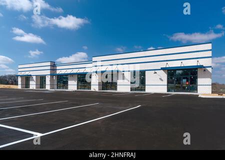 Foto orizzontale di un nuovo centro commerciale business strip costruito con un parcheggio nuovo di zecca con strisce dipinte di fresco. Foto Stock