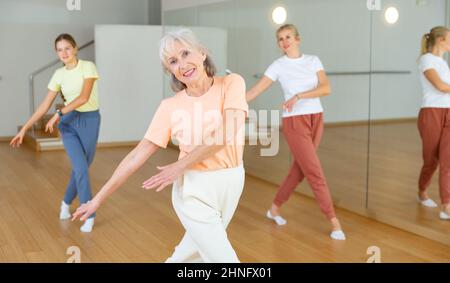 Donna anziana che impara danza aerobica con i suoi parenti più giovani Foto Stock
