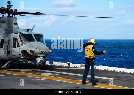 OCEANO PACIFICO (Feb 15, 2022) Aviation Boatswain’s Mate (Handling) 3rd Classe Phillip Harry, nativo di Anniston, Ala., assegnato a nave d’assalto anfibio di classe Wasp USS Essex (LHD 2), segnala a un UH-1Y Huey, attaccato a Marine Medium Tiltrotor Squadron (VMM) 165 (rinforzato), 11th Marine Expeditionary Unit (MEU), durante le operazioni di volo a bordo, 15 febbraio. 2022. Marinai e marines dell'Essex Amphibious Ready Group (ARG) e del MEU 11th stanno conducendo operazioni di routine nella flotta USA 3rd. (STATI UNITI Foto Navy di Mass Communication Specialist 3rd Classe Isaak Martinez) Foto Stock