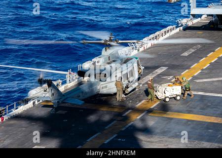 OCEANO PACIFICO (Feb 15, 2022) i Marines effettuano la manutenzione su un UH-1Y Huey, attaccato a Marine Medium Tiltrotor Squadron (VMM) 165 (rinforzato), 11th Marine Expeditionary Unit (MEU), durante le operazioni di volo a bordo di una nave d'assalto anfibio di classe Wasp USS Essex (LHD 2), durante le operazioni di volo, 15 febbraio 2022. Marinai e marines dell'Essex Amphibious Ready Group (ARG) e del MEU 11th stanno conducendo operazioni di routine nella flotta USA 3rd. (STATI UNITI Foto Navy di Mass Communication Specialist 3rd Classe Isaak Martinez) Foto Stock