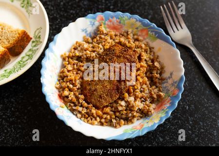 Grano saraceno bollito con cotoletta di carne sul tavolo Foto Stock