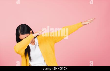 Asian felice ritratto bello cute giovane donna teen sorriso in piedi muoversi mostrando DAB danza contro gesto sollevare le mani braccia coprendo faccia isolata, s. Foto Stock