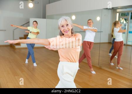 Donna anziana che impara danza aerobica con i suoi parenti più giovani Foto Stock