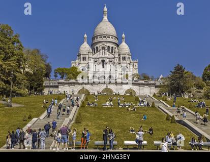 Parigi, Francia-05.05.2018: I turisti sono fotografati di fronte alla collina del tempio di Sacre Coeur. Scale che conducono in su. Giorno di sole, cielo azzurro chiaro Foto Stock