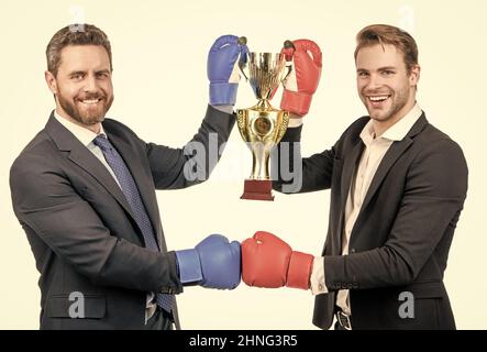 due uomini d'affari felici in guanti di boxe tengono coppa campione dopo la battaglia per la leadership, campionato. Foto Stock