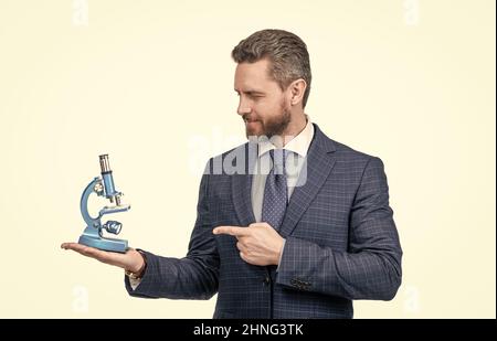 uomo d'affari puntando dito sul microscopio moderno isolato su bianco, scienza e commercio. Foto Stock