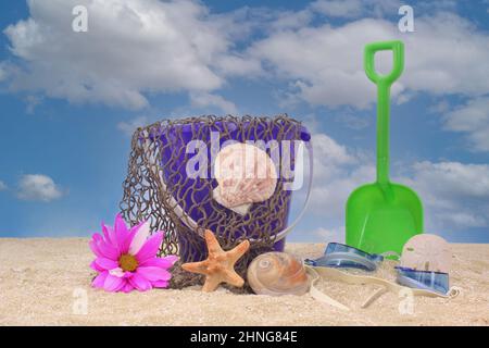Secchio di sabbia con rete e conchiglie di mare su sabbia con cielo Foto Stock