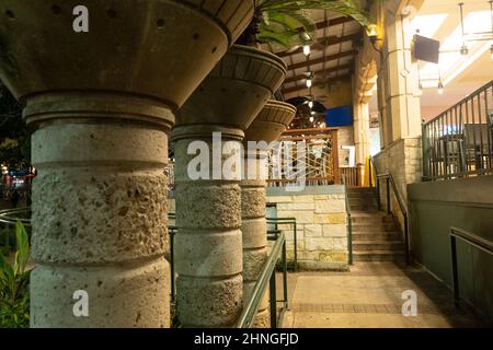 Colonne ornate in pietra di cemento con grande vaso di fiori lungo la passerella con corrimano a mano di notte. Foto Stock