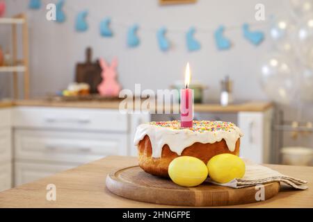 Torta di Pasqua con candela e uova al tavolo in cucina Foto Stock