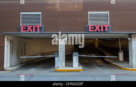Due uscite per la rampa di parcheggio con segnali di uscita rossi sulle porte dove le auto lasciano l'edificio. Foto Stock