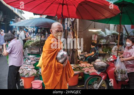 Il suo consueto mattina elemosina rotondo, un monaco buddista, elemosina ciotola in mano, passeggiate attraverso Talat Tok Mor (mercato) a Bangkok, Thailandia Foto Stock