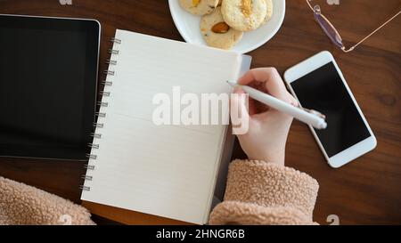 Un blogger freelance che disegna o disegna una certa immagine sul suo taccuino al caffè. Una giovane studentessa universitaria femminile che scrive qualcosa sul quaderno della scuola. Foto Stock