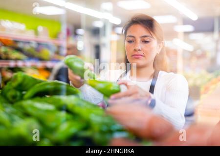 Dipendente donna supermercato in grembiule controllo prodotti Foto Stock