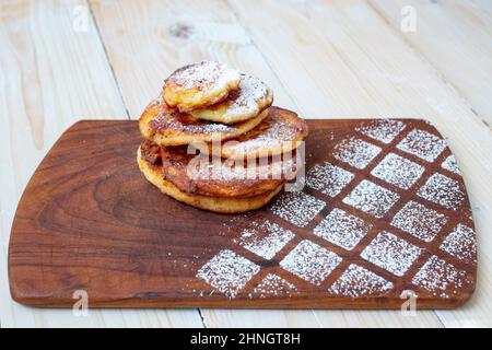 Papanasi rumena o pancake al formaggio casolare su un tritatutto in legno rustico Foto Stock