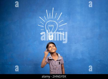 Eccitato Kid con improvvisamente ottenuto o pop up idea espressione sotto leggero doodle su sfondo blu - concetto di bambino trovato soluzione, creatività e. Foto Stock