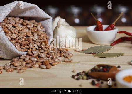 Burlap sacco di fagioli di Pinto sul tavolo con le spezie in background Shalloe DOF Foto Stock