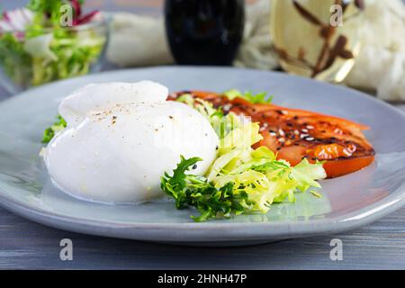 Insalata fresca con burrata, lattuga e pomodori. Delizioso formaggio italiano a base di mozzarella e panna Foto Stock