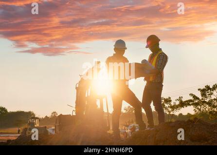 Gli ingegneri stanno lavorando alla costruzione di strade. Ingegnerizzare la comunicazione radio in cantiere con il compattatore a rulli che lavora su strada per la polvere su d Foto Stock