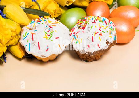Dolci pasquali, uova e tulipani gialli su sfondo beige con spazio per il testo. Foto Stock