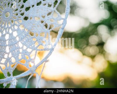 foto ravvicinata di dreamcatcher bianco fatto a mano all'aperto su sfondo naturale sfocato durante il tramonto Foto Stock