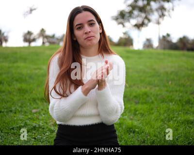 Una giovane donna nel parco si aggrappa alla fotocamera. Foto Stock