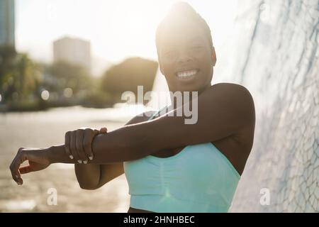 Felice donna africana che fa sport stretching esercizio all'aperto - fuoco morbido sulla mano destra Foto Stock