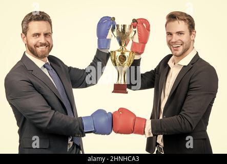 due uomini d'affari felici in guanti di boxe tengono coppa campione dopo la battaglia per la leadership, campionato. Foto Stock