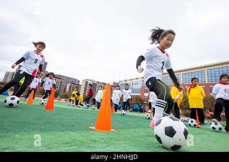 HAI'AN, CINA - 17 FEBBRAIO 2022 - i bambini di una squadra di calcio femminile in una scuola elementare praticano le abilità di base durante le ore di servizio dopo la scuola ad ha Foto Stock