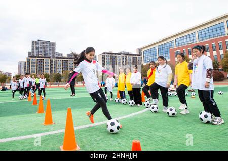 HAI'AN, CINA - 17 FEBBRAIO 2022 - i bambini di una squadra di calcio femminile in una scuola elementare praticano le abilità di base durante le ore di servizio dopo la scuola ad ha Foto Stock