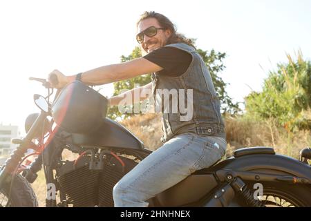 Giovane uomo che indossa occhiali da sole su una moto chopper Foto Stock