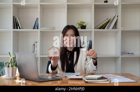 Ritratto asian businesswoman immobiliare mano che tiene il modello e la chiave della casa, vendere il concetto di broker della casa. Foto Stock