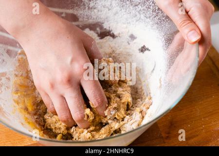 Primo piano delle mani del panettiere della donna impastando l'impasto nel recipiente di miscelazione. Pasticceria fatta in casa per torte o biscotti. Foto Stock