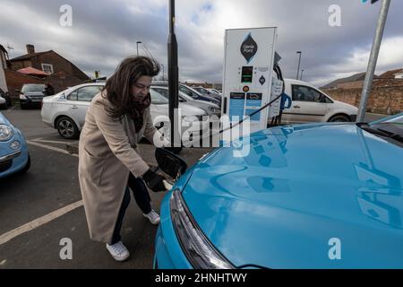 Signora di mezza età che utilizza il punto di ricarica del veicolo "GeniePoint EV Charging" in Hampshire , Inghilterra, Regno Unito Foto Stock