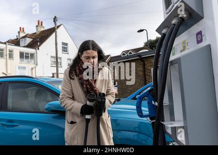 Signora di mezza età che utilizza il punto di ricarica del veicolo "GeniePoint EV Charging" in Hampshire , Inghilterra, Regno Unito Foto Stock