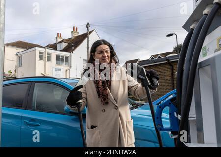 Signora di mezza età che utilizza il punto di ricarica del veicolo "GeniePoint EV Charging" in Hampshire , Inghilterra, Regno Unito Foto Stock