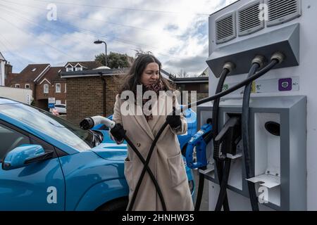 Signora di mezza età che utilizza il punto di ricarica del veicolo "GeniePoint EV Charging" in Hampshire , Inghilterra, Regno Unito Foto Stock