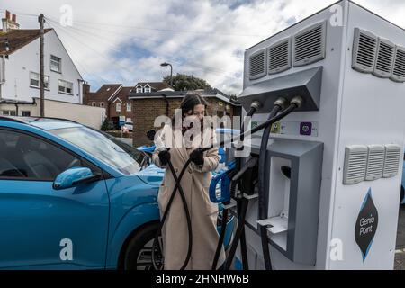 Signora di mezza età che utilizza il punto di ricarica del veicolo "GeniePoint EV Charging" in Hampshire , Inghilterra, Regno Unito Foto Stock