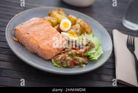 filetto di salmone al forno con spicchi di patate fritte, guacamole fatte in casa e metà uova di quaglia Foto Stock