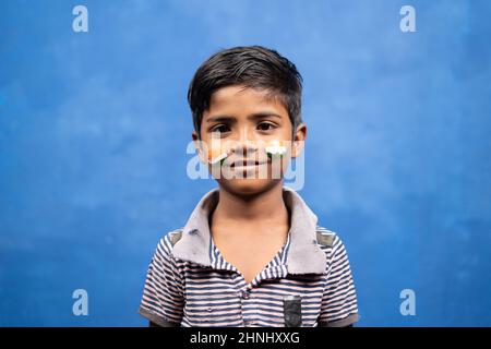 Ritratto di bambino sorridente in t shirt strappata con bandiera indiana sul volto guardando la macchina fotografica - concetto di povertà, nazionalismo e libertà Foto Stock